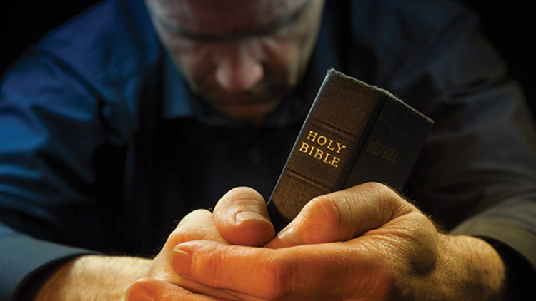 Man in prayer holding bible